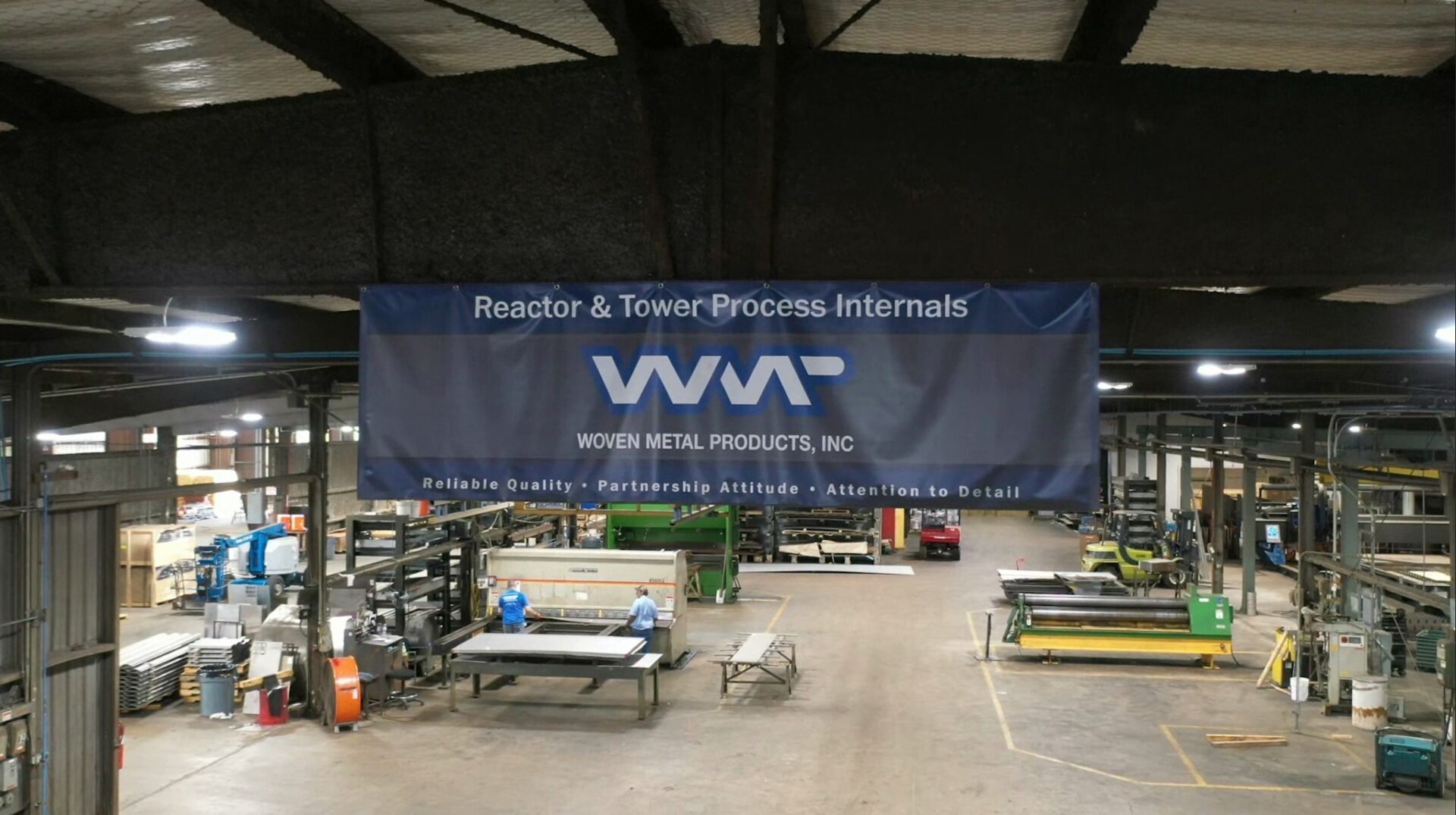 Interior view of the Woven Metal Products manufacturing shop floor, featuring a large banner for Reactor & Tower Process Internals.